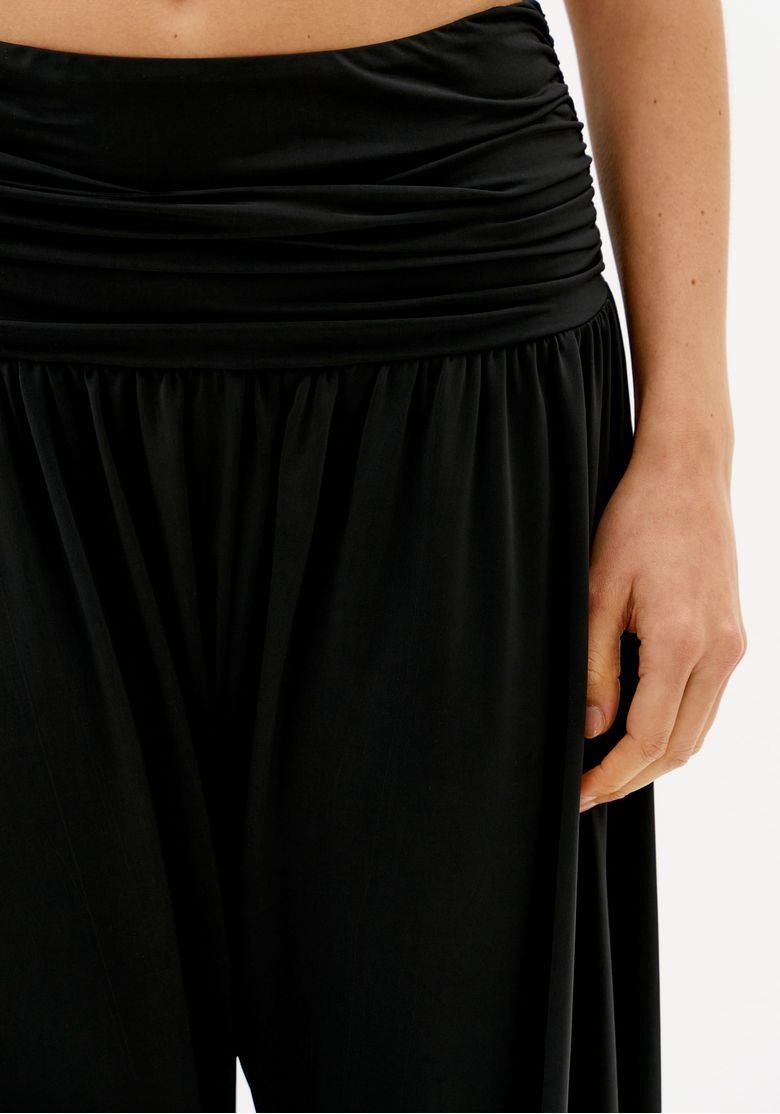 Detalhe do cós franzido da calça saruel preta de malha com cintura média e caimento solto