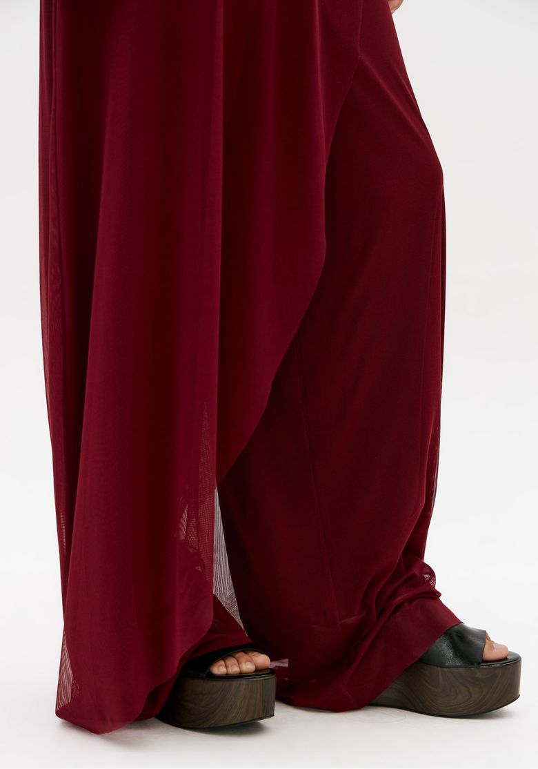 Detalhe da barra longa da calça bordô com tule transparente e movimento leve