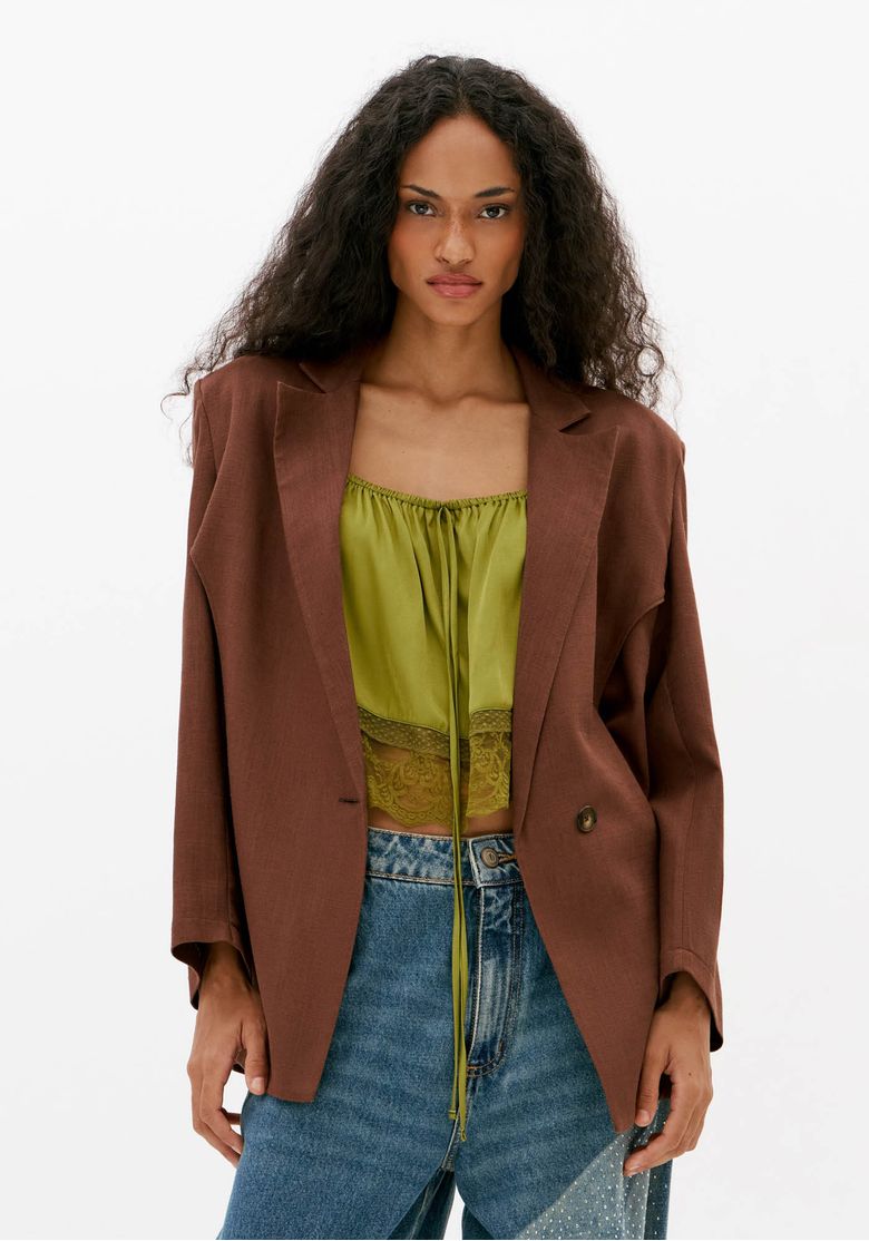 Mulher-usando-blazer-feminino-marrom-de-linho-com-lapela-classica-manga-longa-e-botao-frontal-combinado-com-blusa-verde-e-jeans-amplo