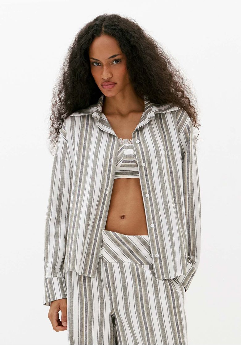 Modelo-usando-camisa-oversized-feminina-listrada-off-white-com-linho-aberta-sobre-top-em-look-de-moda-contemporanea