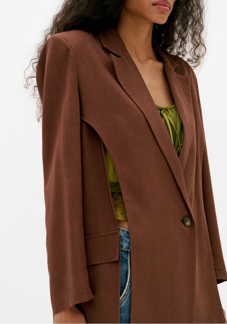 Close-do-blazer-feminino-marrom-com-lapela-classica-bolso-com-aba-e-fechamento-por-um-botao-em-tecido-leve-com-linho