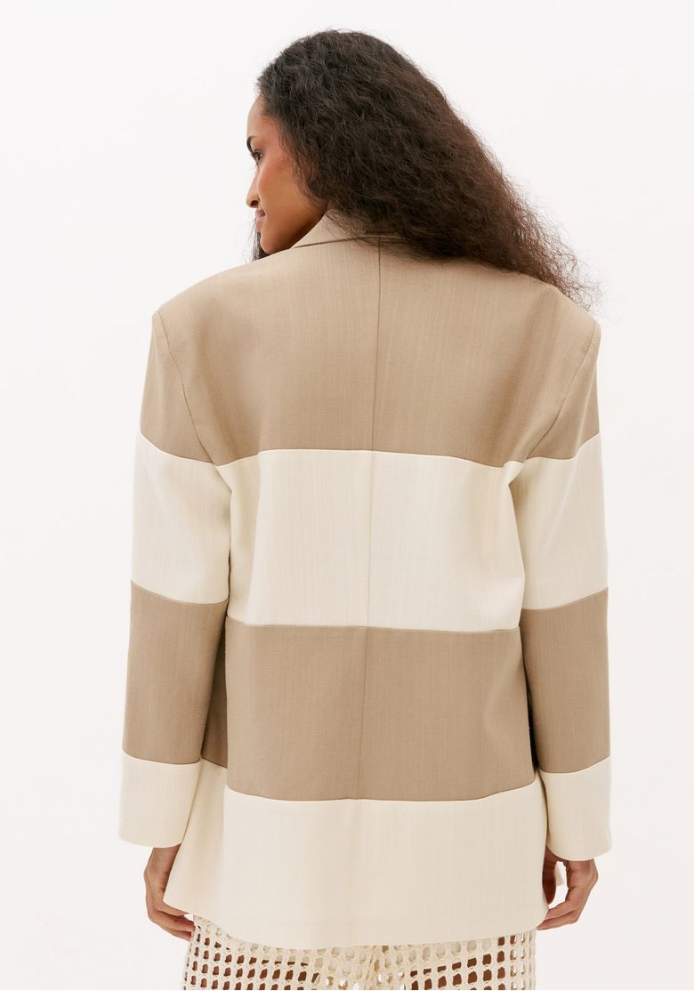 Blazer feminino bicolor bege e off white visto de costas, modelagem oversized com mangas longas e recortes horizontais