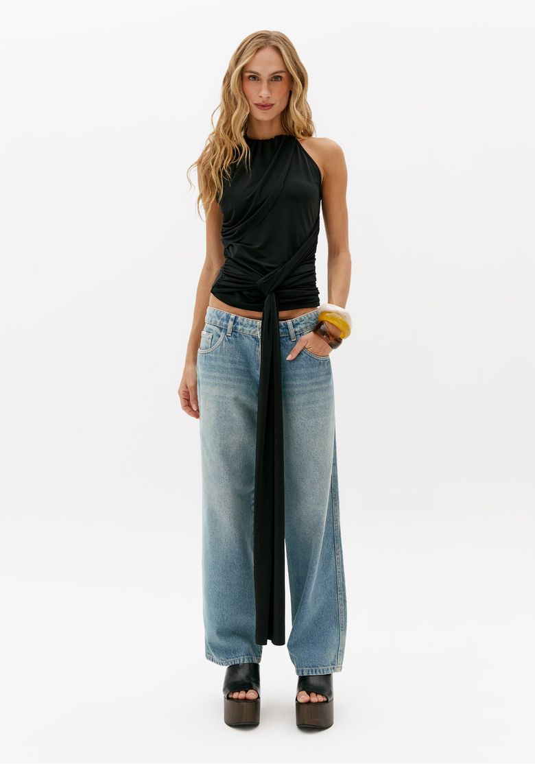 Look completo com blusa preta sem manga com amarração longa e calça jeans wide leg clara