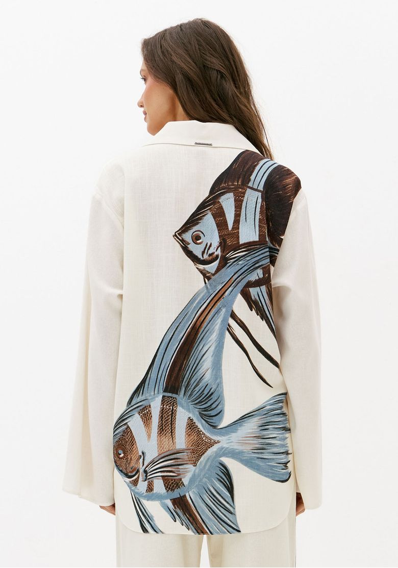 Vista traseira de camisa feminina alongada branca com linho e estampa de peixes nas costas, modelagem ampla e manga longa