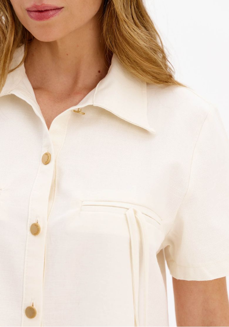 Close-da-camisa-cropped-off-white-feminina-mostrando-colarinho-classico-botoes-frontais-dourados-e-detalhe-dos-bolsos