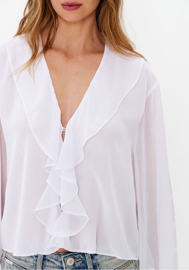 Close-da-blusa-branca-com-babado-frontal-em-cascata-decote-em-V-e-mangas-longas-transparentes
